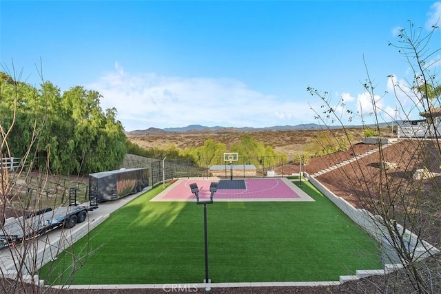 view of sport court with a mountain view, a yard, community basketball court, and fence