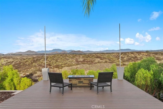 wooden terrace with a fire pit and a mountain view