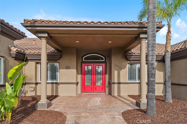 entrance to property featuring a tiled roof, stucco siding, and french doors