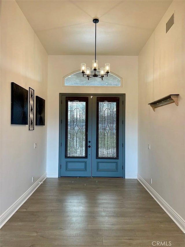 entrance foyer with visible vents, wood finished floors, baseboards, and a chandelier