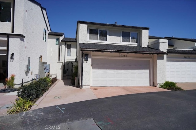 townhome / multi-family property with aphalt driveway, stucco siding, and a garage