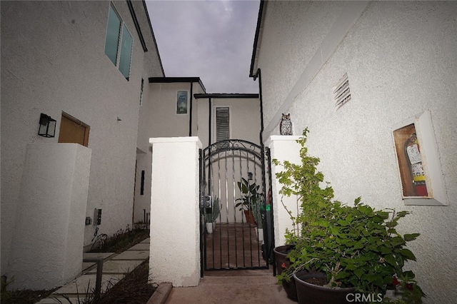 entrance to property featuring stucco siding and a gate