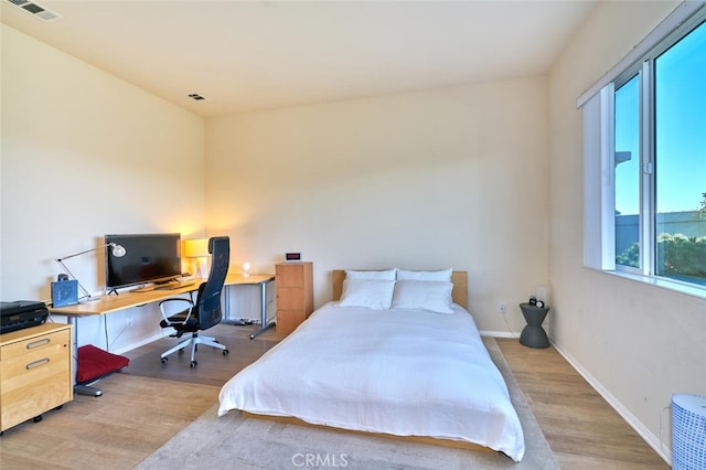 bedroom with light wood-type flooring, visible vents, and baseboards