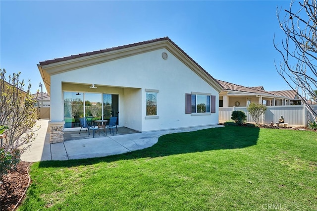 rear view of house with a tiled roof, fence, a yard, a patio area, and stucco siding