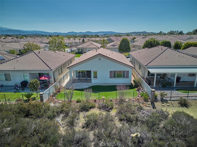 back of house featuring a fenced backyard, a residential view, a yard, a patio area, and a mountain view