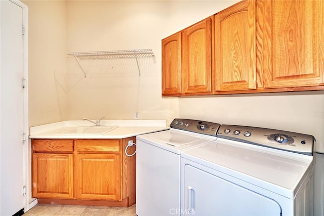 washroom with cabinet space, a sink, and washing machine and clothes dryer