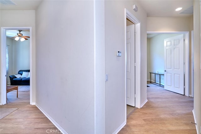 corridor with visible vents, light wood-style flooring, and baseboards