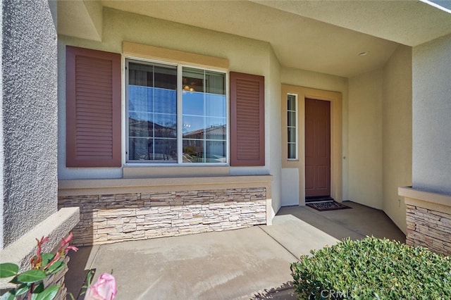 view of exterior entry featuring stone siding and stucco siding