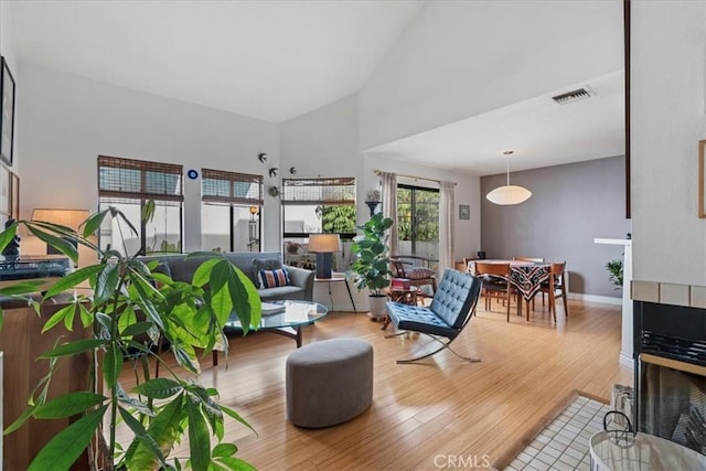 living room with visible vents, high vaulted ceiling, baseboards, and wood finished floors