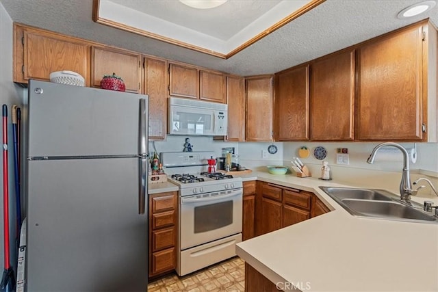 kitchen with a sink, white appliances, light floors, and light countertops