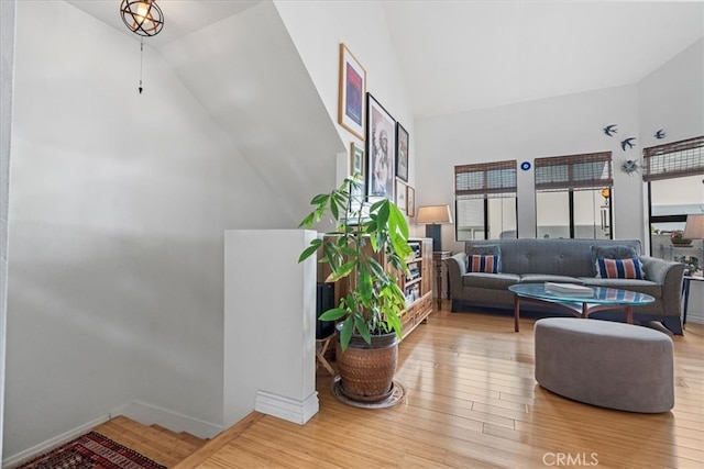 living room featuring wood finished floors, baseboards, and high vaulted ceiling