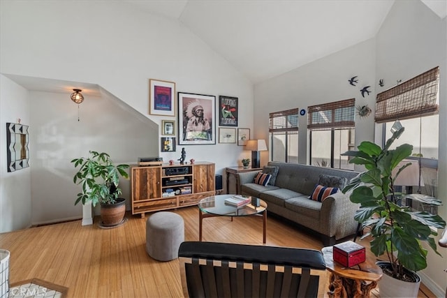 living room with wood finished floors, baseboards, and high vaulted ceiling