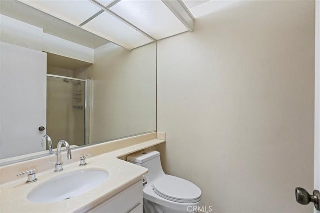 bathroom featuring toilet, a stall shower, and vanity