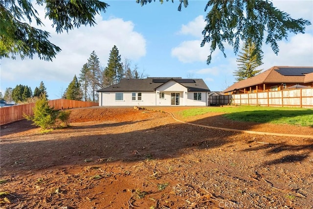 back of property featuring solar panels, a lawn, and a fenced backyard