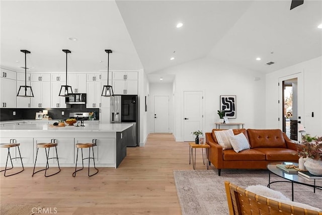 kitchen featuring stainless steel appliances, a breakfast bar, white cabinetry, and light wood finished floors