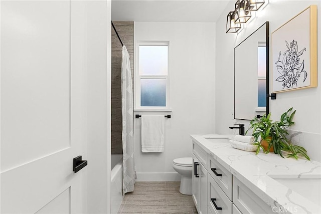 full bathroom with double vanity, toilet, a sink, wood finished floors, and baseboards