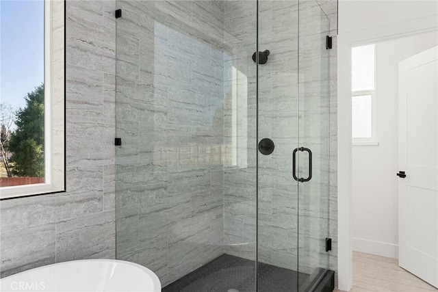 bathroom featuring a stall shower, a wealth of natural light, and a freestanding bath