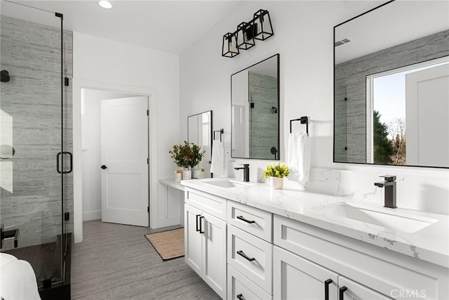 bathroom with a stall shower, a sink, and double vanity