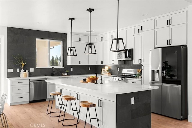 kitchen with light wood-style flooring, a breakfast bar area, a center island, stainless steel appliances, and a sink