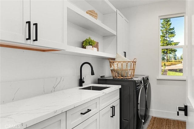 laundry room featuring washing machine and clothes dryer, a sink, cabinet space, and baseboards