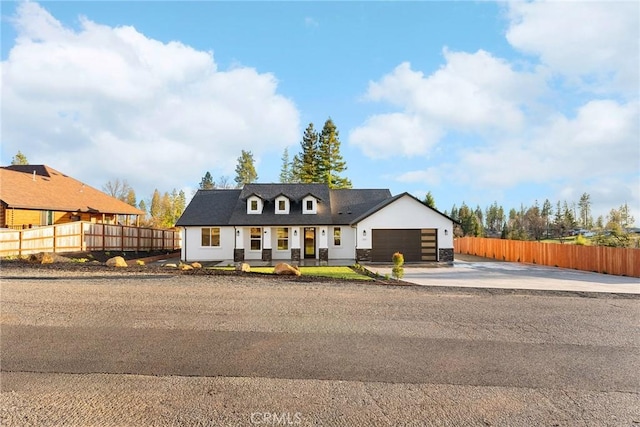 view of front of property featuring a garage, concrete driveway, and fence