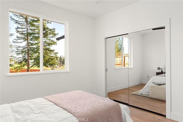 bedroom with light wood finished floors, baseboards, and a closet