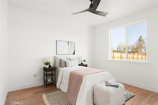 bedroom with ceiling fan, light wood finished floors, and baseboards