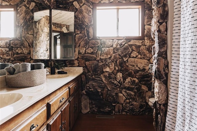 bathroom featuring a wealth of natural light, wood finished floors, a sink, and double vanity