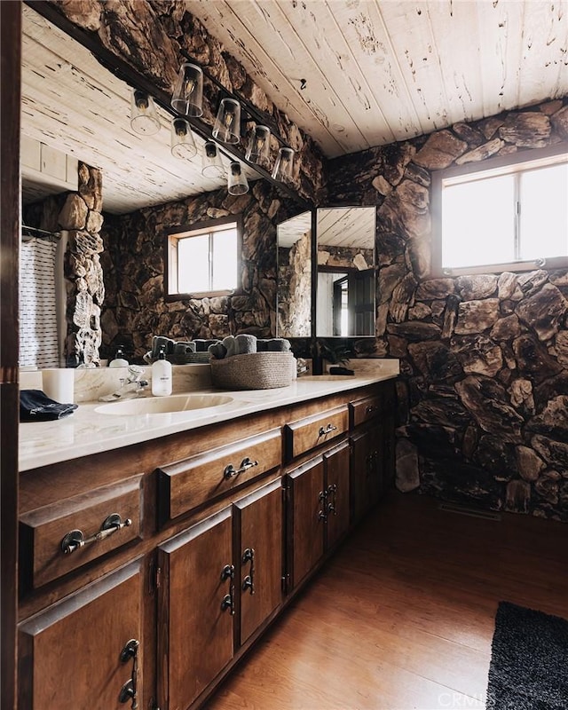 bathroom with wood finished floors, wooden ceiling, a sink, and a wealth of natural light