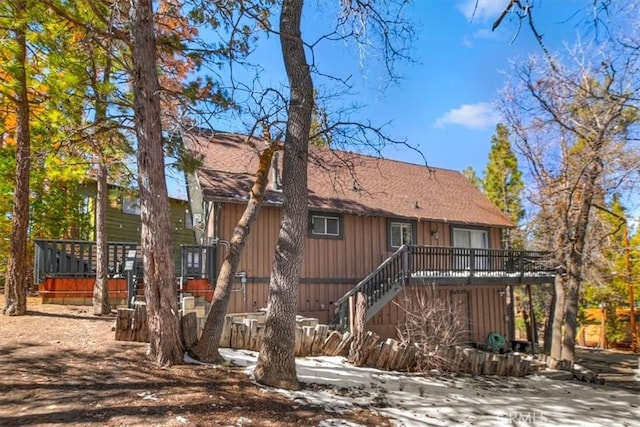 view of front of house featuring a shingled roof, stairway, and a wooden deck