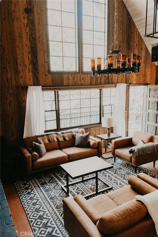 living room featuring high vaulted ceiling and wood walls