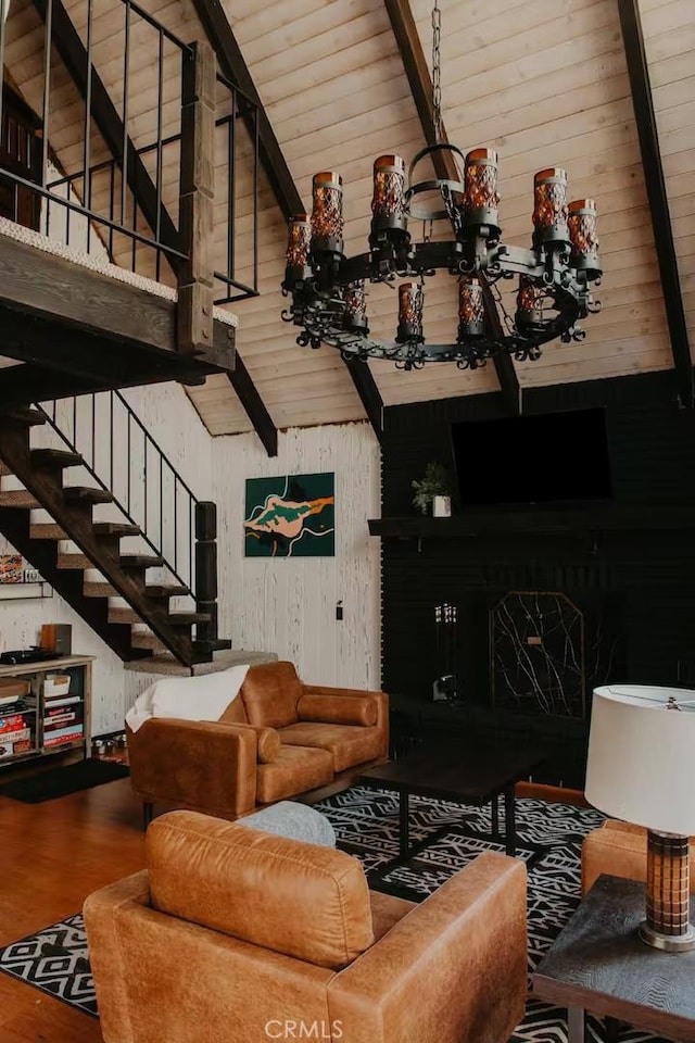 living room with stairway, a fireplace, wood finished floors, and an inviting chandelier