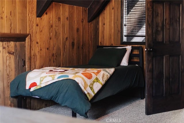 carpeted bedroom featuring wood walls