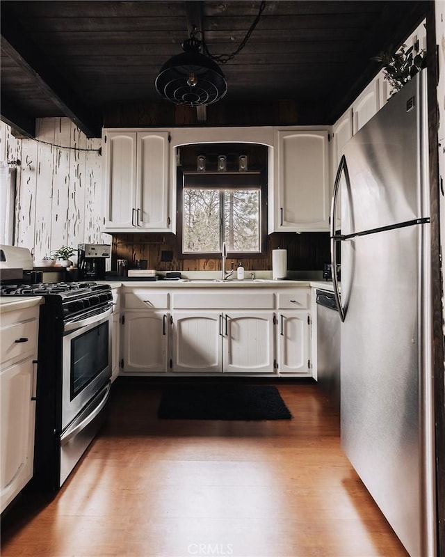 kitchen with appliances with stainless steel finishes, white cabinetry, a sink, and dark wood-type flooring