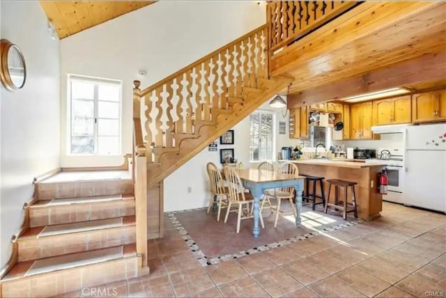 dining room featuring stairs, light tile patterned floors, lofted ceiling, and wood ceiling