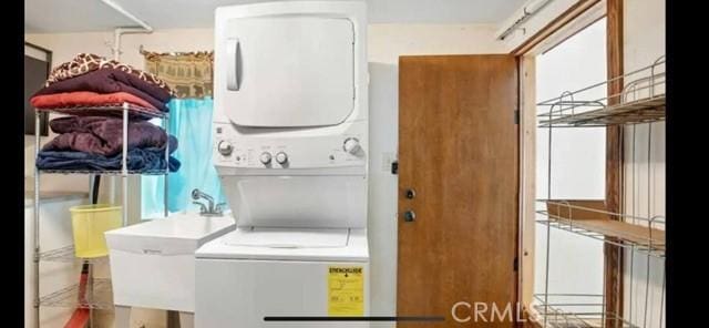 clothes washing area with stacked washer and dryer, a sink, and laundry area