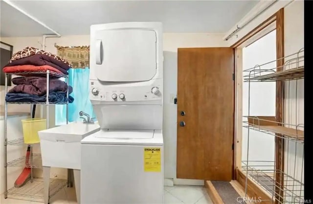 laundry room featuring laundry area, light tile patterned floors, a sink, and stacked washer and clothes dryer