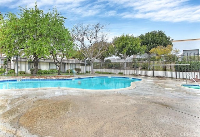 community pool with a patio and fence