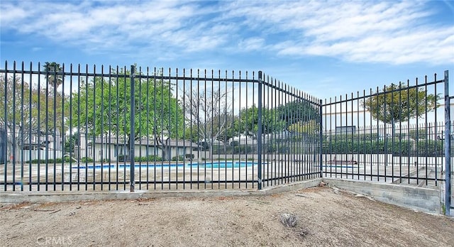 view of gate featuring fence and a community pool