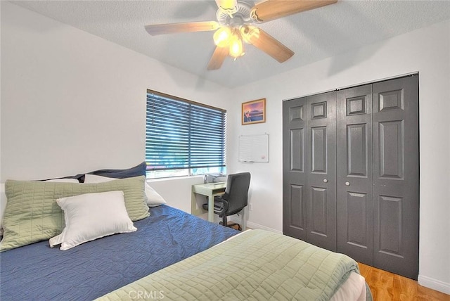 bedroom with baseboards, a ceiling fan, wood finished floors, a textured ceiling, and a closet