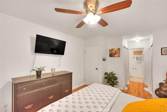 bedroom with light wood-type flooring, baseboards, a textured ceiling, and ensuite bathroom