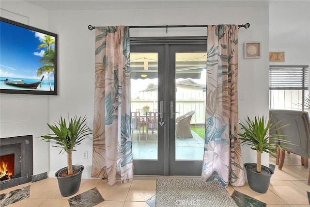 doorway featuring tile patterned flooring, french doors, and a lit fireplace