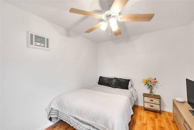 bedroom with visible vents, light wood-style floors, ceiling fan, a textured ceiling, and baseboards