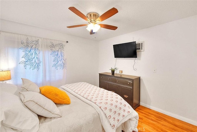 bedroom with baseboards, ceiling fan, a textured ceiling, and light wood finished floors