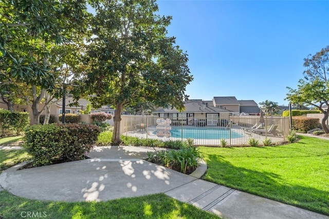 community pool featuring a patio area, a lawn, and fence