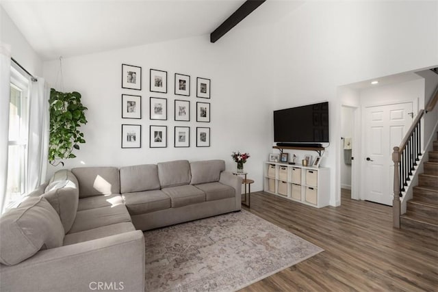 living area featuring beam ceiling, stairway, wood finished floors, and a wealth of natural light