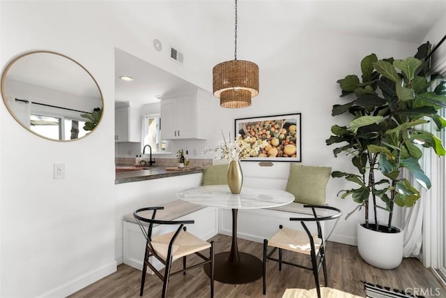 dining room featuring visible vents, breakfast area, baseboards, and wood finished floors