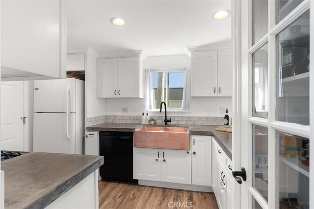 kitchen with dark countertops, freestanding refrigerator, black dishwasher, and a sink