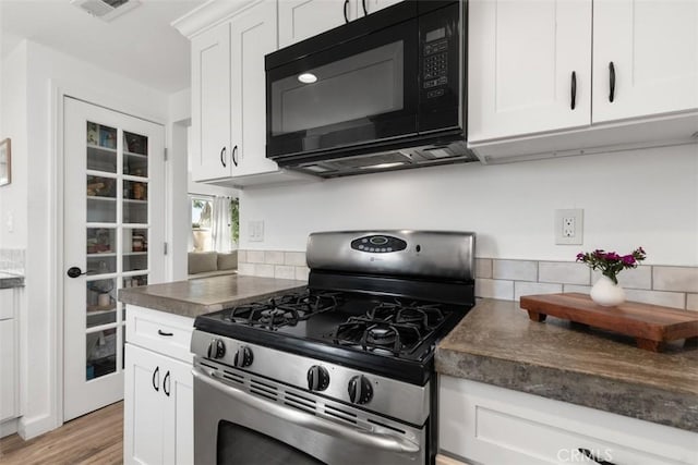 kitchen with visible vents, dark countertops, white cabinetry, stainless steel range with gas cooktop, and black microwave