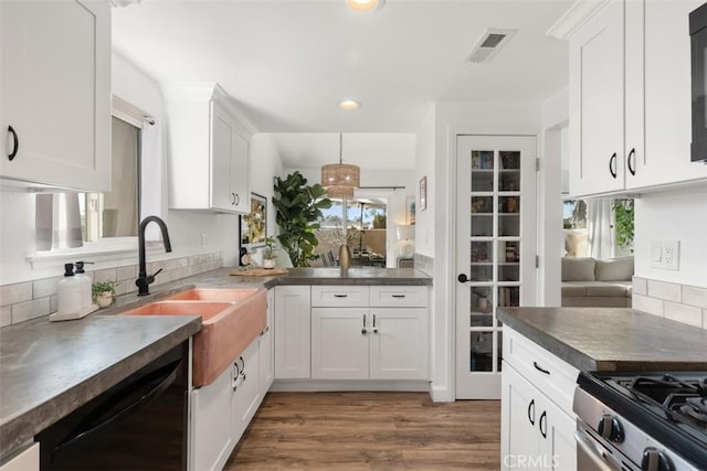 kitchen featuring wood finished floors, visible vents, stainless steel range with gas cooktop, black dishwasher, and white cabinetry